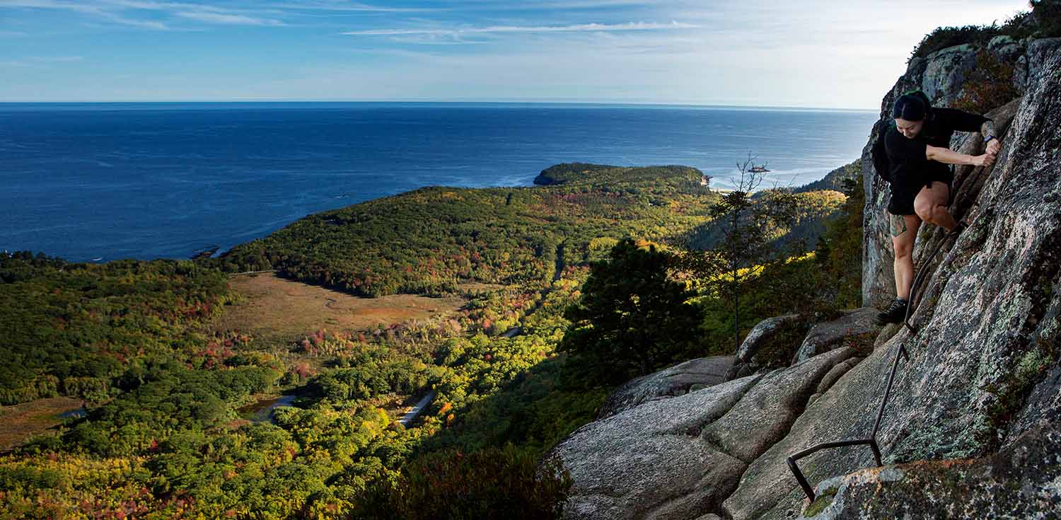 A hiker uses iron rungs to climb up the Precipice Trail in Acadia National Park. (Photo by Ashley L. Conti/Friends of Acadia)