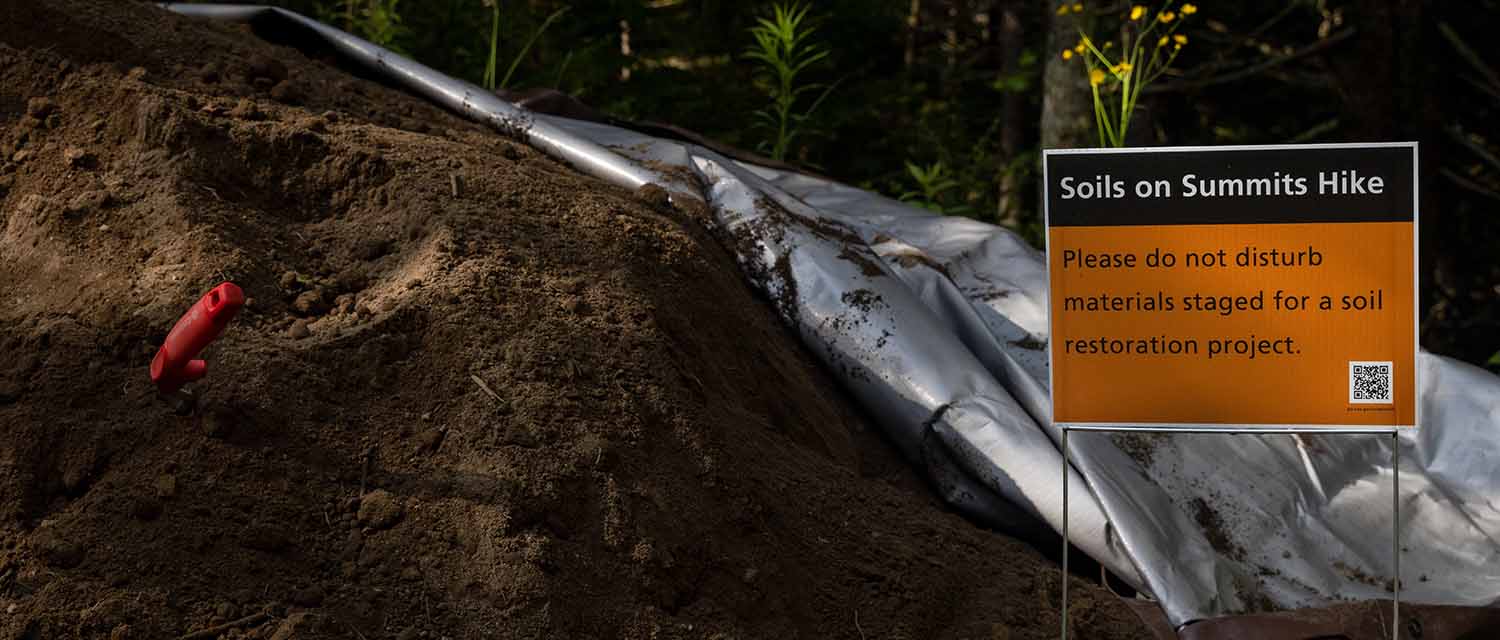 A sign next to a pile of soil educates visitors along the carriage roads during the Soil on Summits hike up Sargent and Penobscot Mountains in Acadia National Park. (Photo by Sam Mallon/Friends of Acadia)